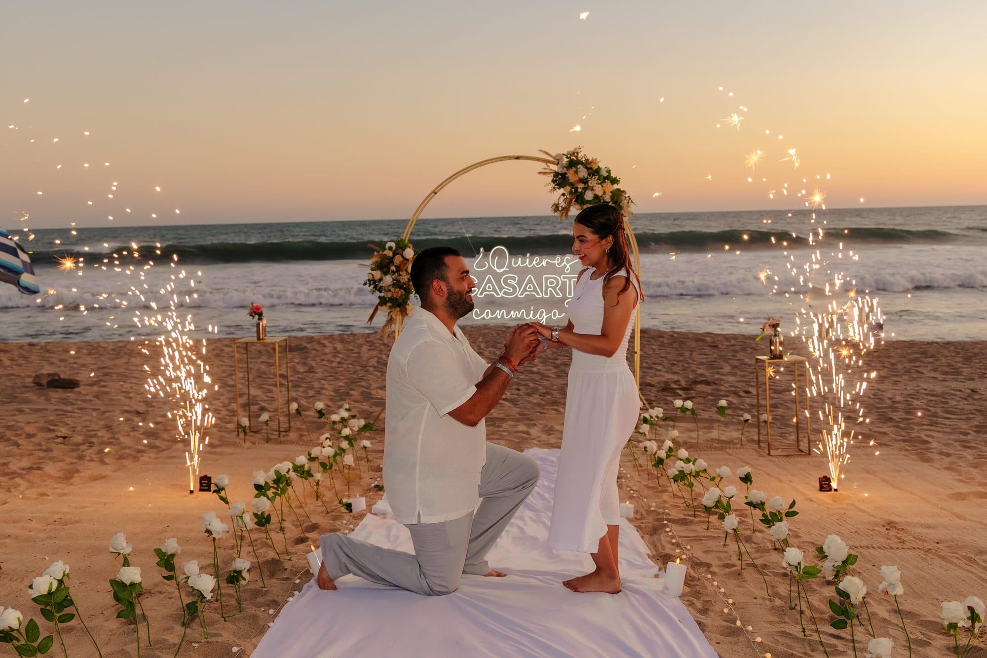Propuesta de matrimonio en la playa con chispas al atardecer